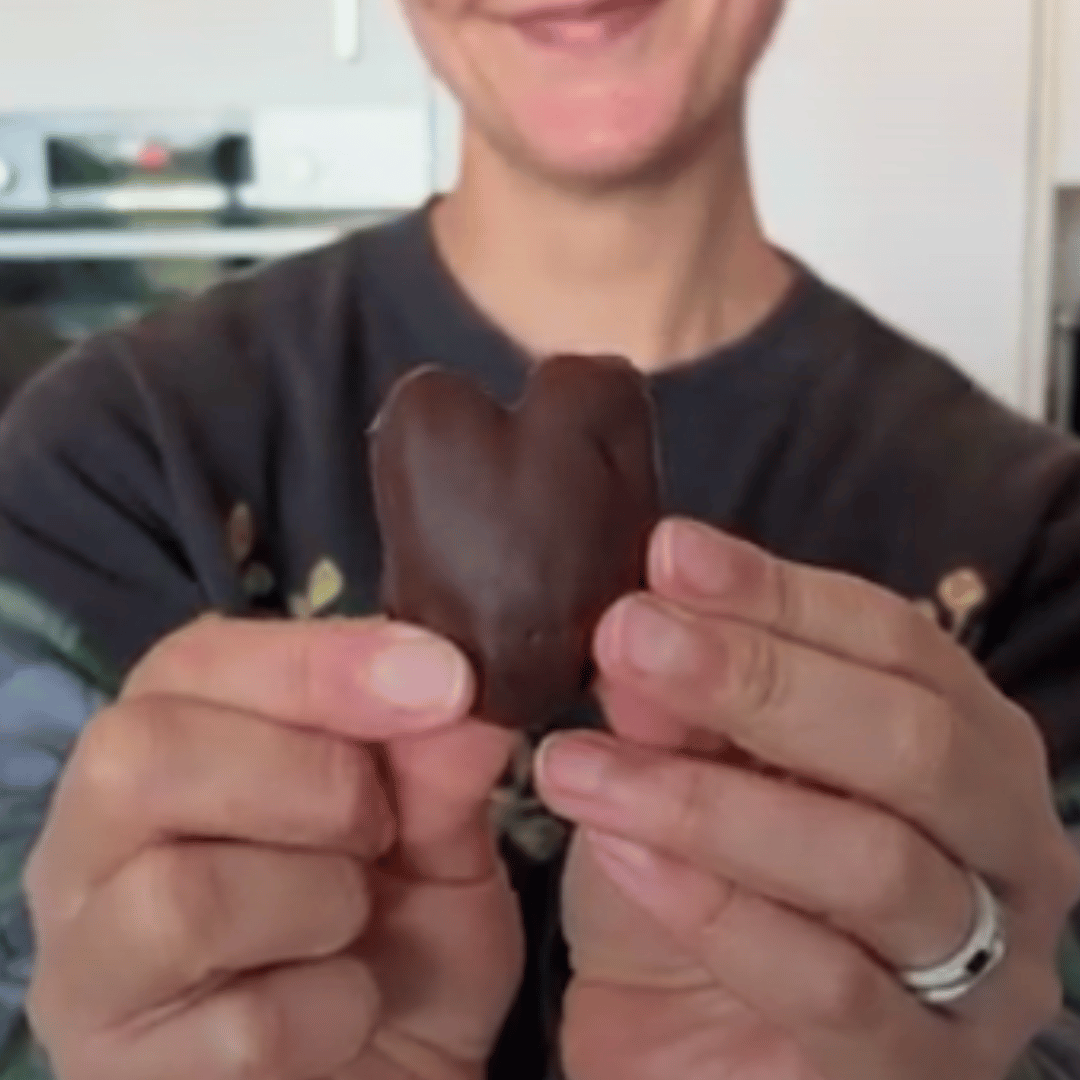 Image of a woman holding a chocolate heart shaped date in her hands