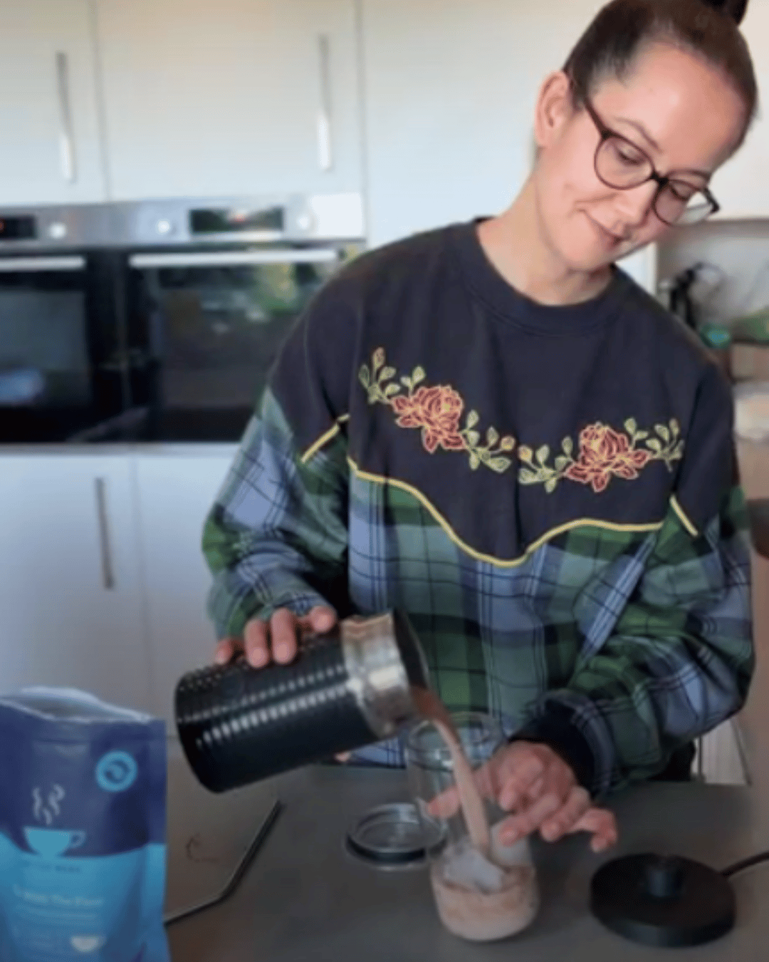 Woman in a gingham sweatshirt making a Go With The Flow Milkshake