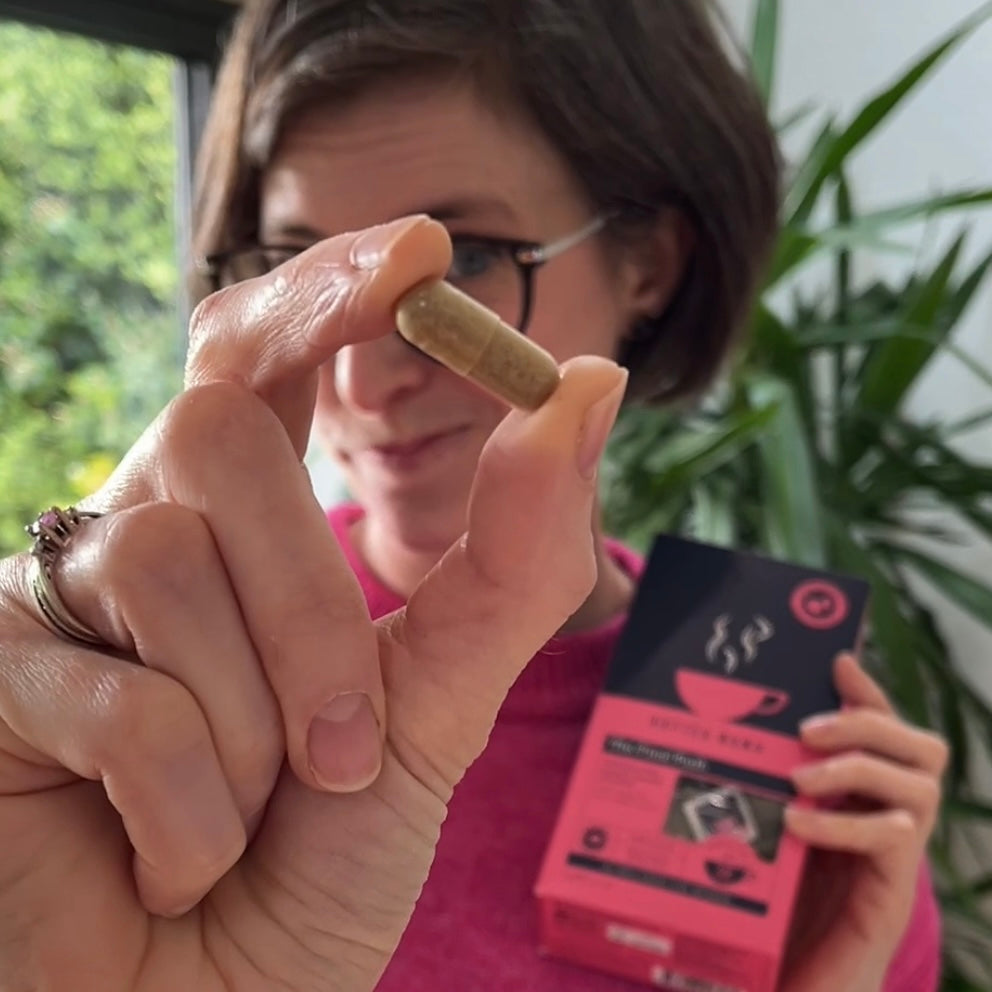 Raspberry leaf capsule being held up to camera by a lady with pink jumper on, who is also holding a pack of HotTea Mama The Final Push raspberry leaf tea