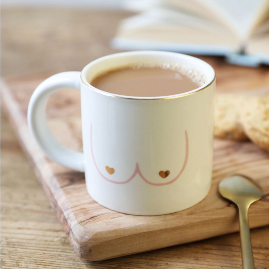 HotTea Mama boobies mug on wooden chopping board with tea in it and biscuits and a spoon next to it